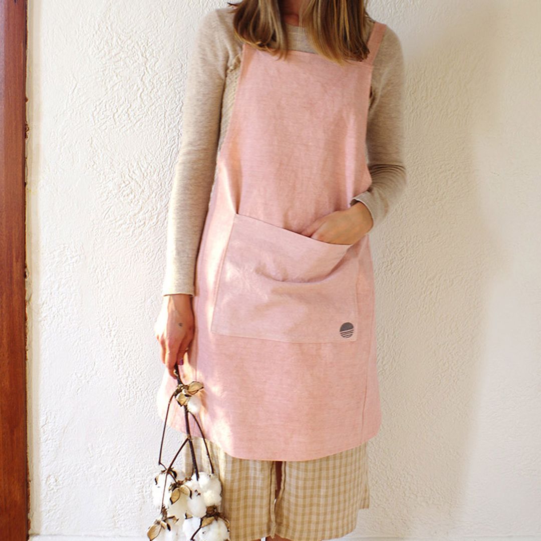 lady wearing pink apron and white flowers against white concrete wall