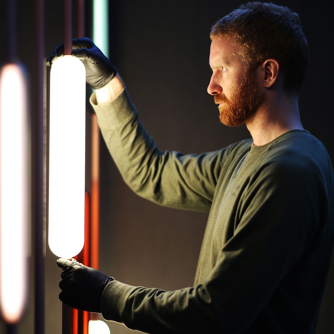 Man-wearing-green-shirt-placing-cylinder-light-on-dark-wall